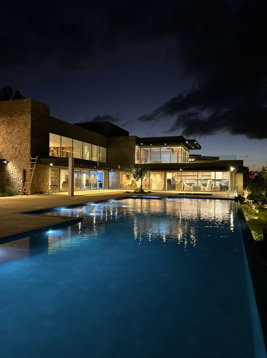 Vista ampla de residência de alto padrão com iluminação externa e piscina