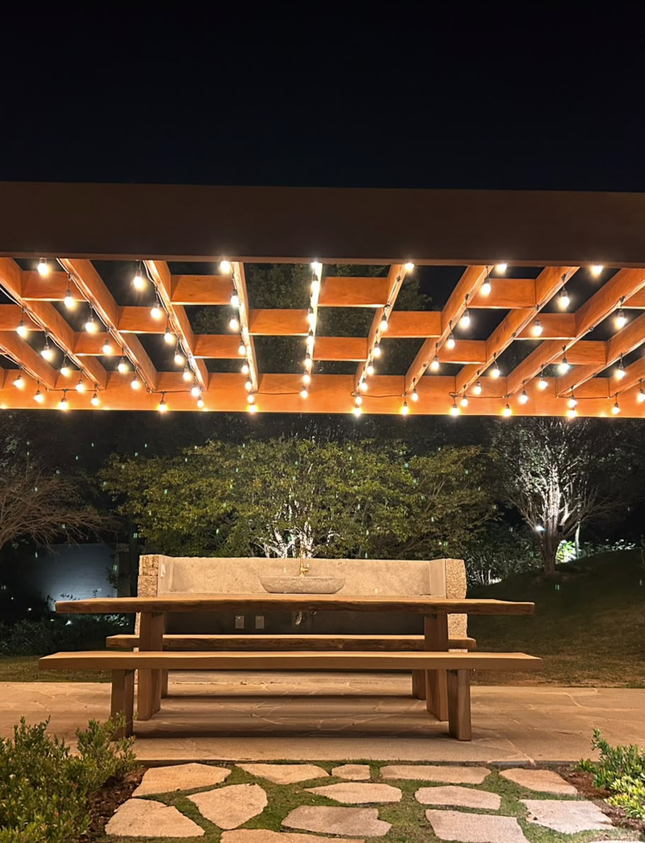 Pergolado de madeira com iluminação decorativa e área externa integrada